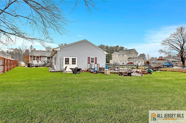 back of property featuring a residential view, a yard, and fence