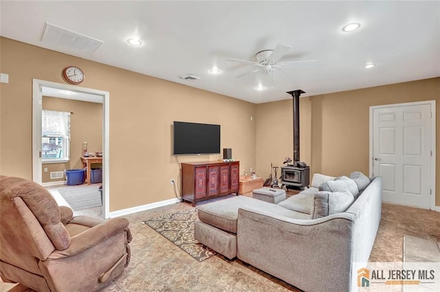 living area with baseboards, visible vents, a ceiling fan, a wood stove, and recessed lighting