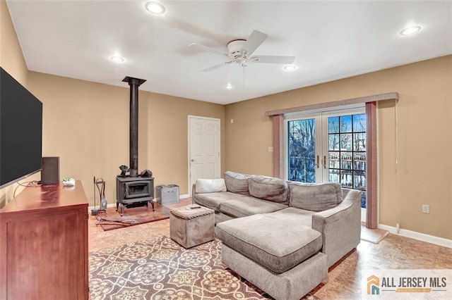 living area with french doors, recessed lighting, a ceiling fan, a wood stove, and baseboards