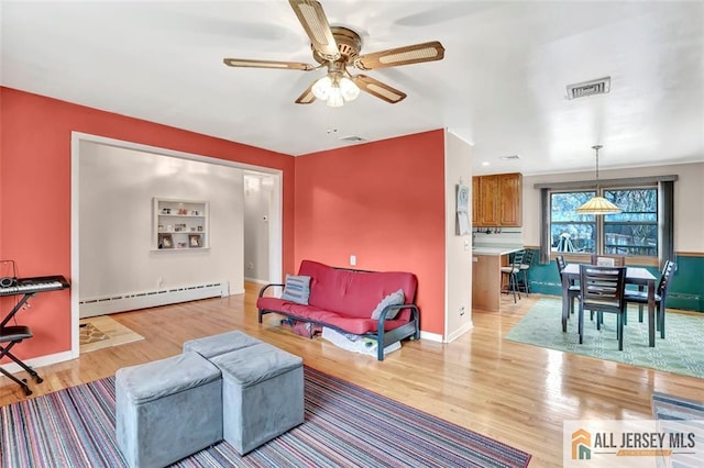 living room with a ceiling fan, visible vents, light wood finished floors, and baseboard heating