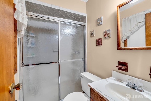 bathroom with walk in shower, vanity, and toilet