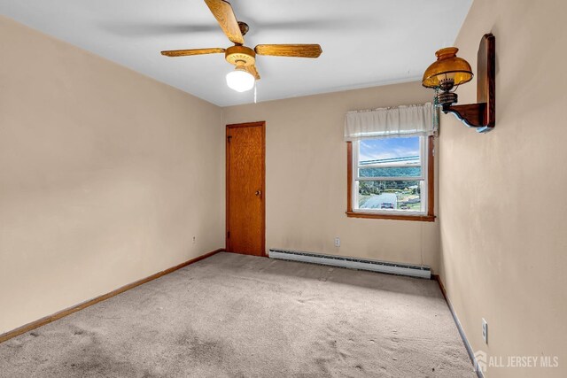 carpeted spare room featuring ceiling fan and a baseboard heating unit