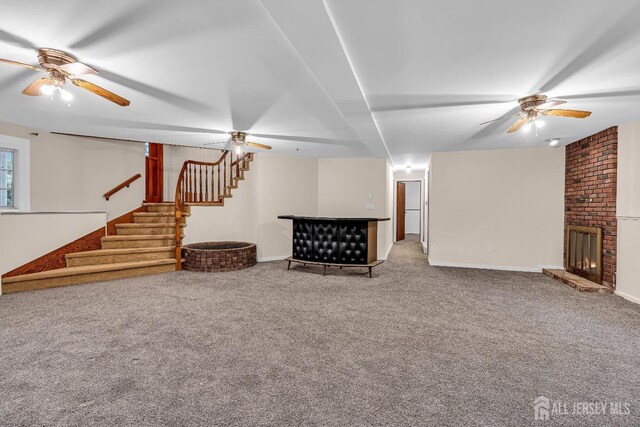 unfurnished living room featuring carpet, a brick fireplace, and ceiling fan