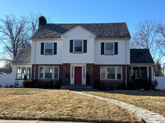 view of front facade featuring a sunroom and a front lawn