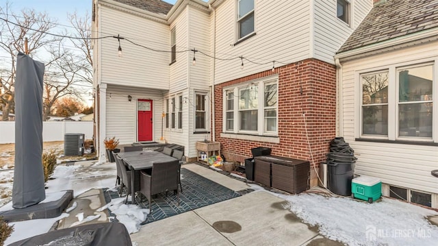 snow covered patio featuring fence and central AC