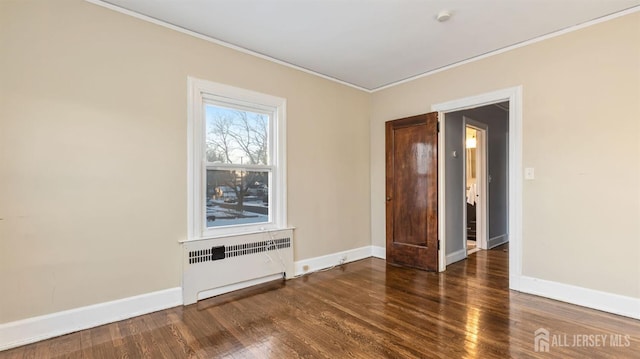 spare room with baseboards, radiator, and wood finished floors