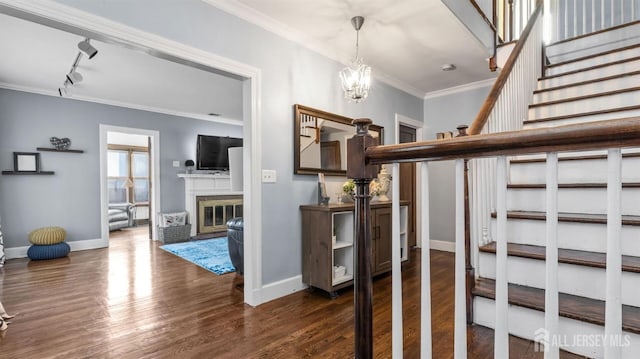 staircase with a glass covered fireplace, baseboards, wood finished floors, and ornamental molding