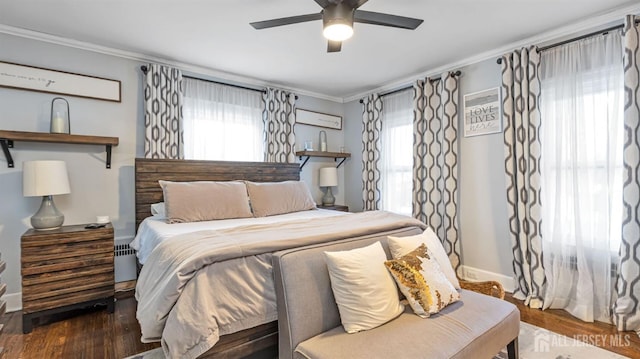 bedroom featuring ornamental molding, wood finished floors, and multiple windows