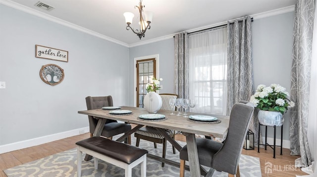 dining room featuring wood finished floors, visible vents, and ornamental molding