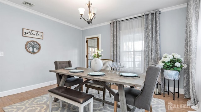 dining area with a chandelier, crown molding, visible vents, and baseboards