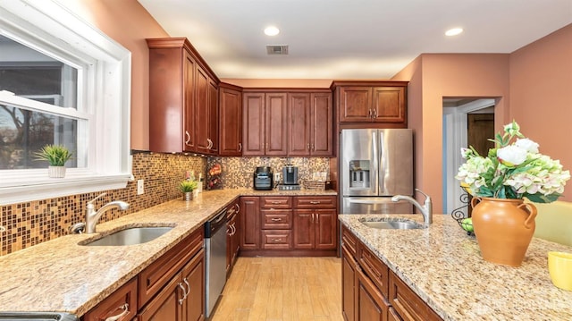 kitchen with visible vents, backsplash, appliances with stainless steel finishes, and a sink