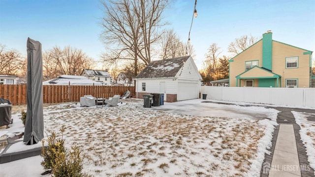 yard covered in snow featuring a detached garage, a patio, an outdoor structure, and fence