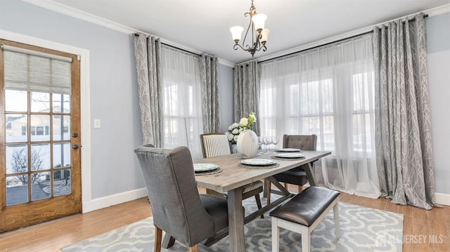 dining space with a chandelier, baseboards, wood finished floors, and crown molding