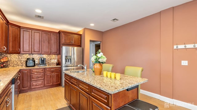 kitchen featuring light wood-type flooring, visible vents, light stone counters, and stainless steel appliances