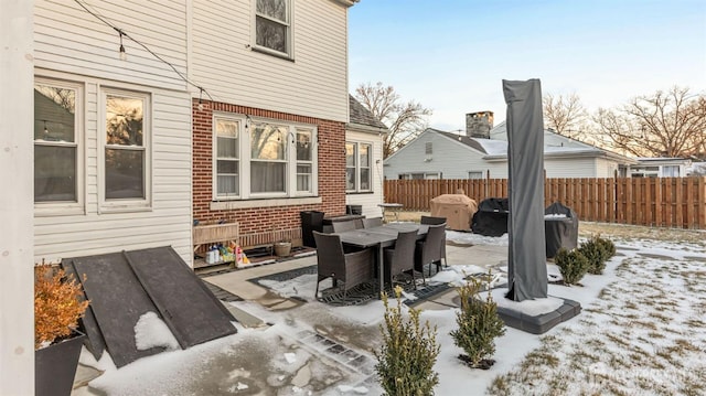 snow covered patio with outdoor dining area and fence