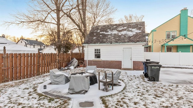 snow covered patio with an outbuilding and a fenced backyard