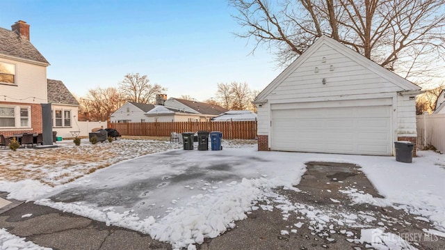 snow covered garage featuring fence and a garage