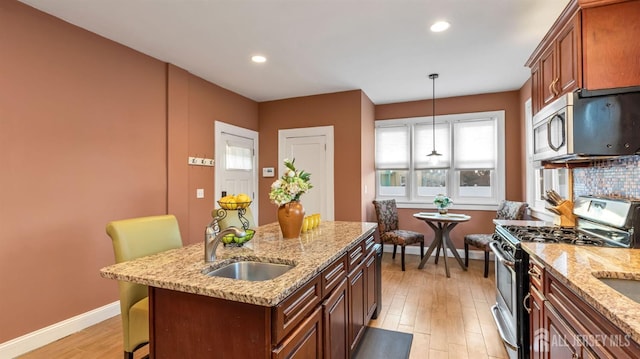 kitchen featuring a center island, baseboards, light wood-type flooring, stainless steel appliances, and a sink