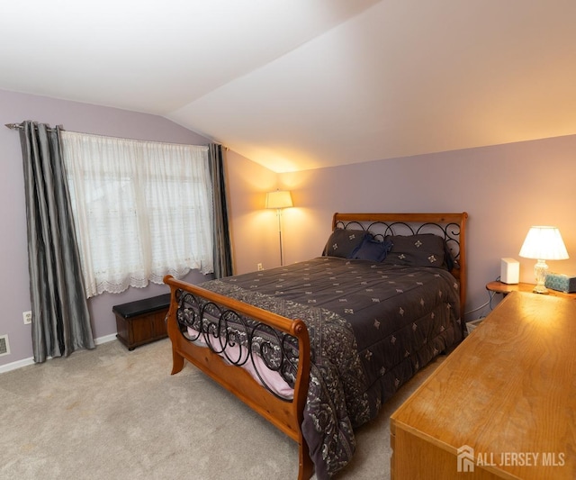 bedroom with vaulted ceiling, visible vents, and light colored carpet