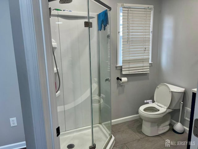 bathroom with toilet, tile patterned floors, and a shower with door