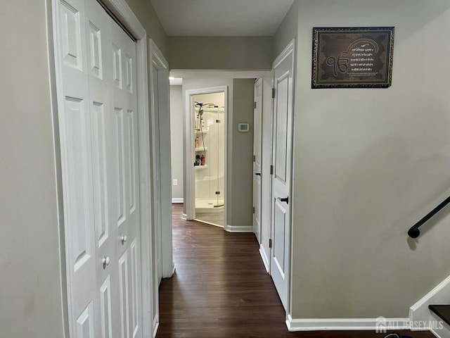 corridor with dark wood-style flooring and baseboards