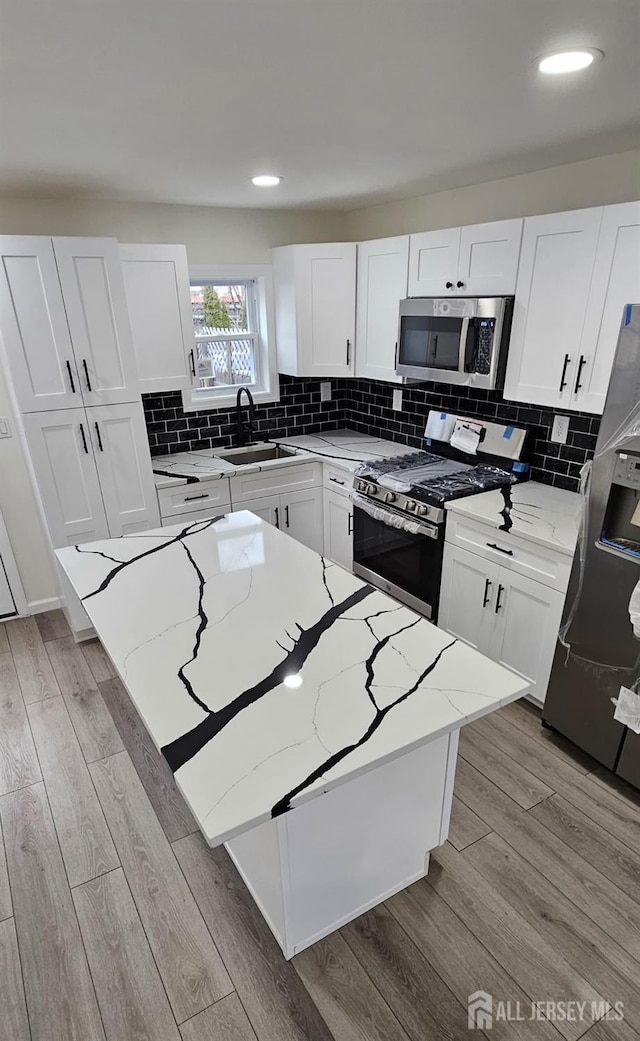 kitchen with white cabinetry, light stone countertops, appliances with stainless steel finishes, and sink