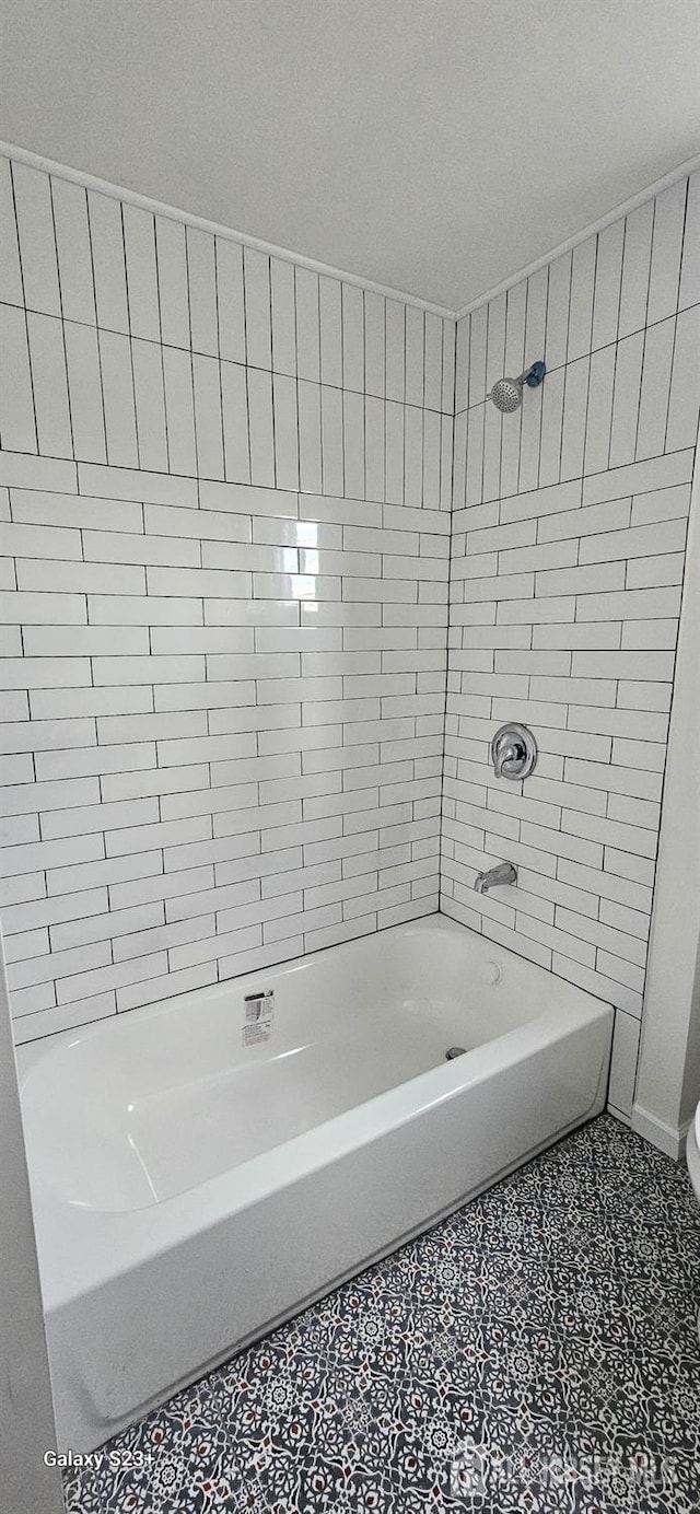 bathroom featuring tile patterned floors, toilet, and tiled shower / bath combo