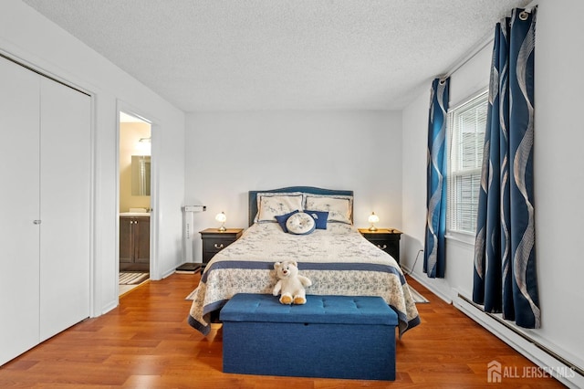 211 Rossmoor Dr Unit B, Monroe, NJ 08831 - bedroom featuring a baseboard heating unit, a textured ceiling, wood finished floors, and connected bathroom