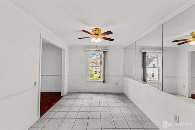 spare room featuring baseboards, a ceiling fan, and crown molding