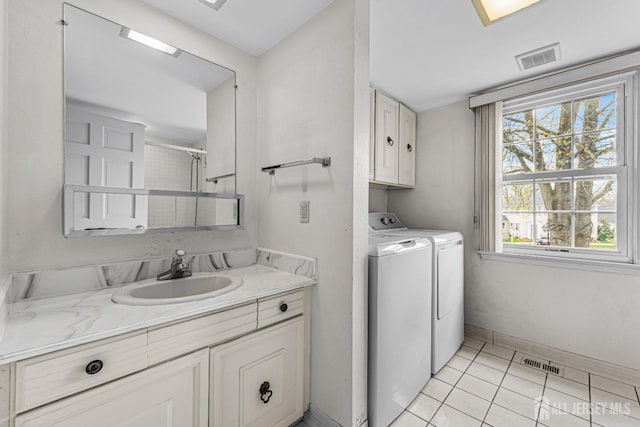 washroom with a sink, a healthy amount of sunlight, visible vents, washer and dryer, and cabinet space