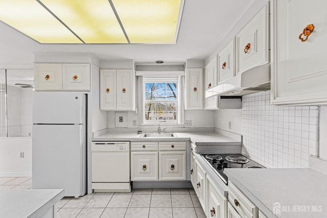 kitchen featuring a sink, under cabinet range hood, light tile patterned floors, white cabinetry, and white appliances
