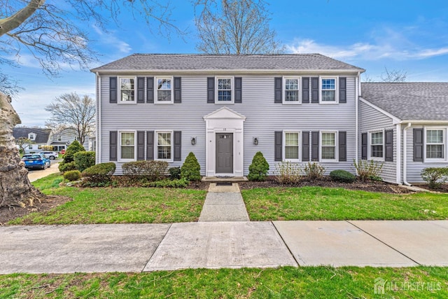 colonial-style house featuring a front lawn