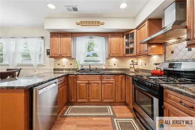39 Evergreen Ter, Monroe, NJ 08831 - kitchen with stainless steel appliances, wall chimney exhaust hood, light wood-style flooring, brown cabinets, and a peninsula