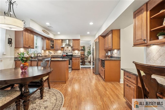 39 Evergreen Ter, Monroe, NJ 08831 - kitchen with stainless steel appliances, wall chimney exhaust hood, brown cabinets, dark countertops, and light wood-type flooring
