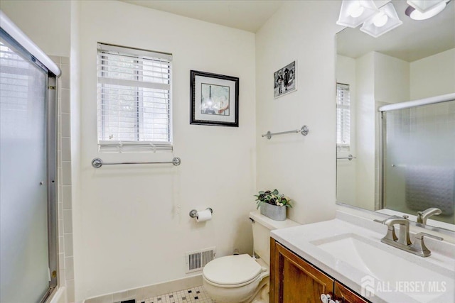 bathroom featuring vanity, toilet, and a shower with shower door