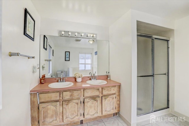 bathroom with tile patterned floors, a shower with door, vanity, and toilet