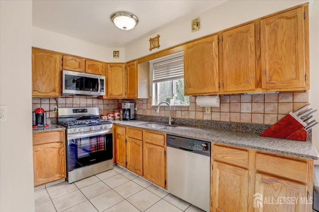 kitchen with light tile patterned floors, sink, appliances with stainless steel finishes, and tasteful backsplash