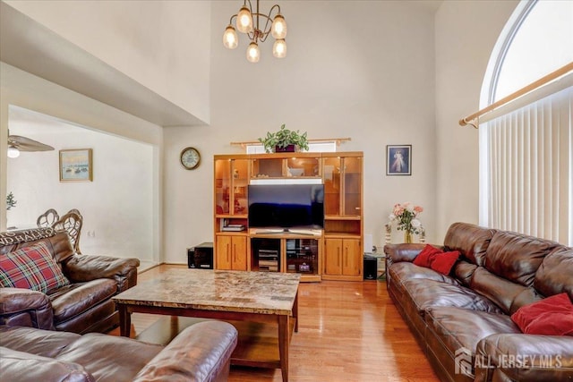 living room with a high ceiling, light hardwood / wood-style flooring, and a notable chandelier