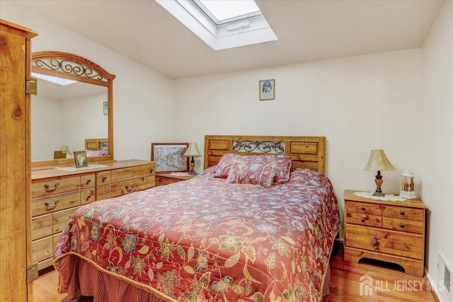 bedroom with hardwood / wood-style floors and a skylight