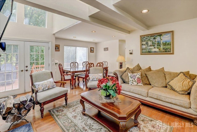 living room featuring beamed ceiling, light hardwood / wood-style flooring, and french doors