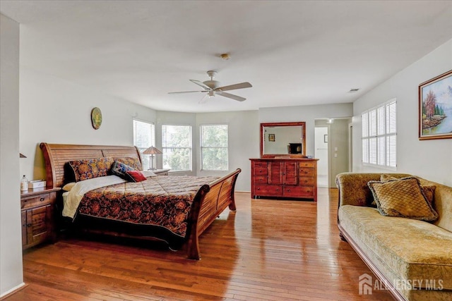 bedroom with ceiling fan, multiple windows, and light hardwood / wood-style flooring