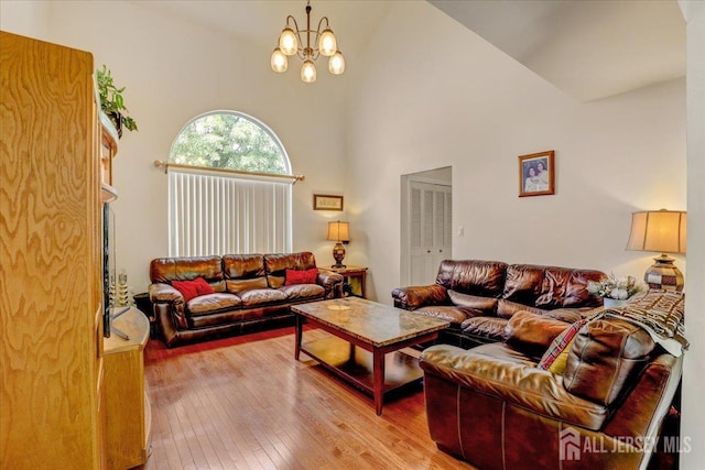 living room with hardwood / wood-style floors, a notable chandelier, and high vaulted ceiling