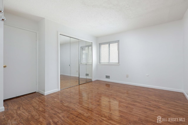 55 Smith St, Perth Amboy, NJ 08861 - unfurnished bedroom featuring wood finished floors, a textured ceiling, and a closet