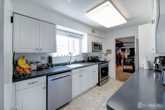 55 Smith St, Perth Amboy, NJ 08861 - kitchen featuring appliances with stainless steel finishes, dark countertops, white cabinetry, and a textured ceiling