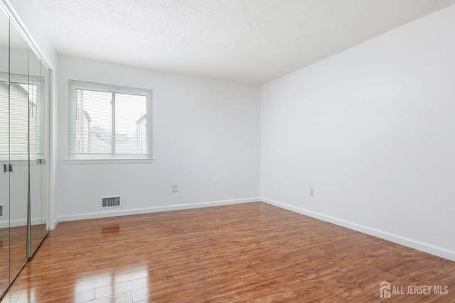55 Smith St, Perth Amboy, NJ 08861 - unfurnished bedroom with wood finished floors, a textured ceiling, and a closet