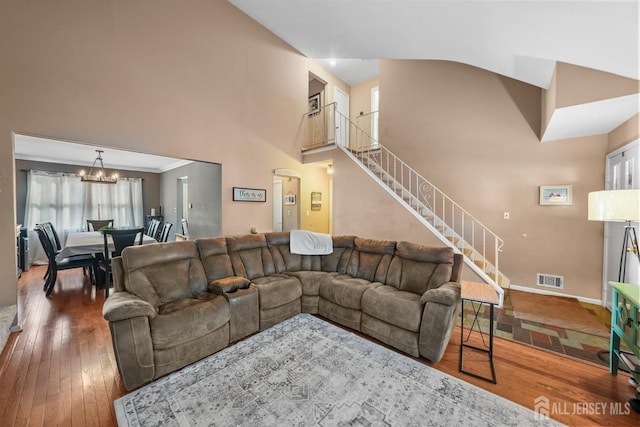 living area with stairs, high vaulted ceiling, wood-type flooring, and visible vents