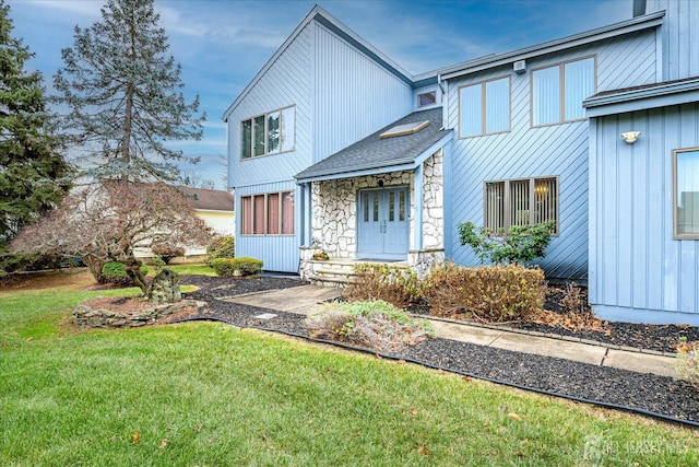 modern inspired farmhouse featuring stone siding, board and batten siding, and a front lawn