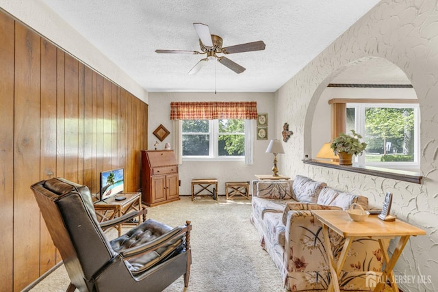 92 Maplewood Ave, Edison, NJ 08837 - living room with a textured ceiling, ceiling fan, carpet, arched walkways, and wooden walls
