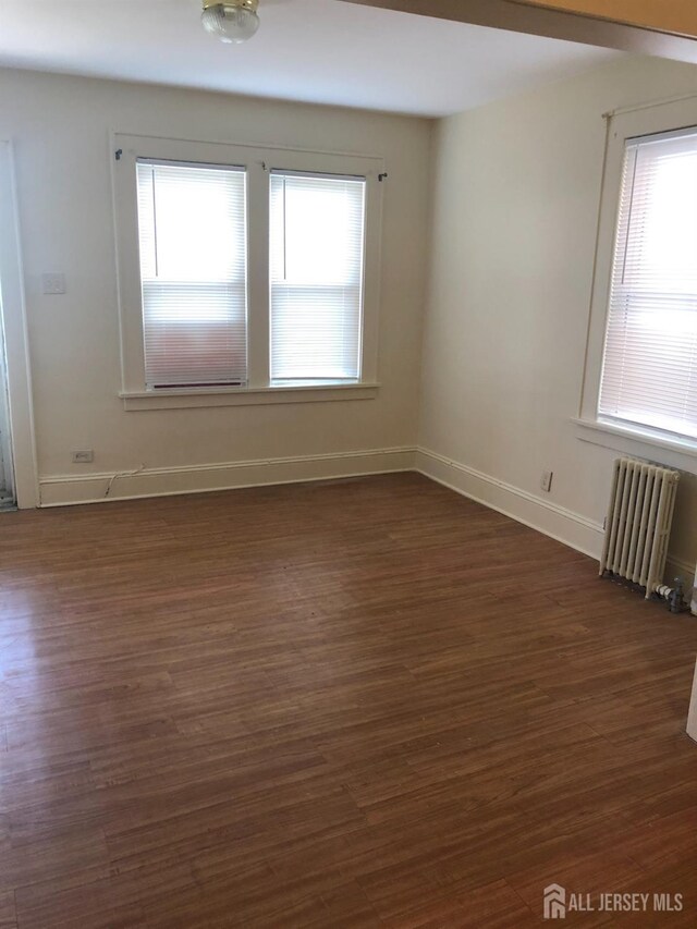 spare room with dark hardwood / wood-style flooring and radiator heating unit