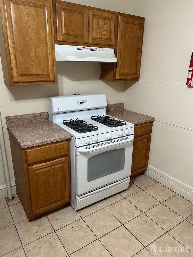 kitchen with under cabinet range hood, white gas range oven, and brown cabinets